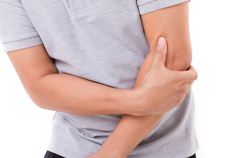 man holding his elbow from pain that can be treated by a chiropractor in Boca Raton