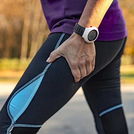 A woman in exercise clothing holding her leg with sciatic pain